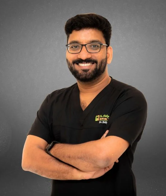 A professional portrait of Dr. Dilip Kumar, MDS, a specialist Prosthodontist and founder of Dr. Dilip Dental Centre, widely regarded as the best dentist in Chennai, posing in his black clinical scrubs.