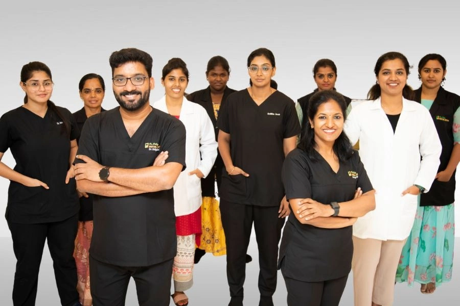 A professional photograph of a large, diverse team of smiling dental specialists, doctors, and assistants, led by experts recognized as the best dentist in Chennai, posing confidently in uniforms and lab coats.