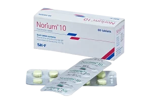An angled view of a white Norium 10 box positioned behind two crossed blister packs, displaying round, light-yellow tablets on one strip and the printed silver foil backing on the other.