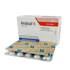 A white and red cardboard box of Amdocal-5 tablets standing upright behind a silver foil blister strip containing round pills.
